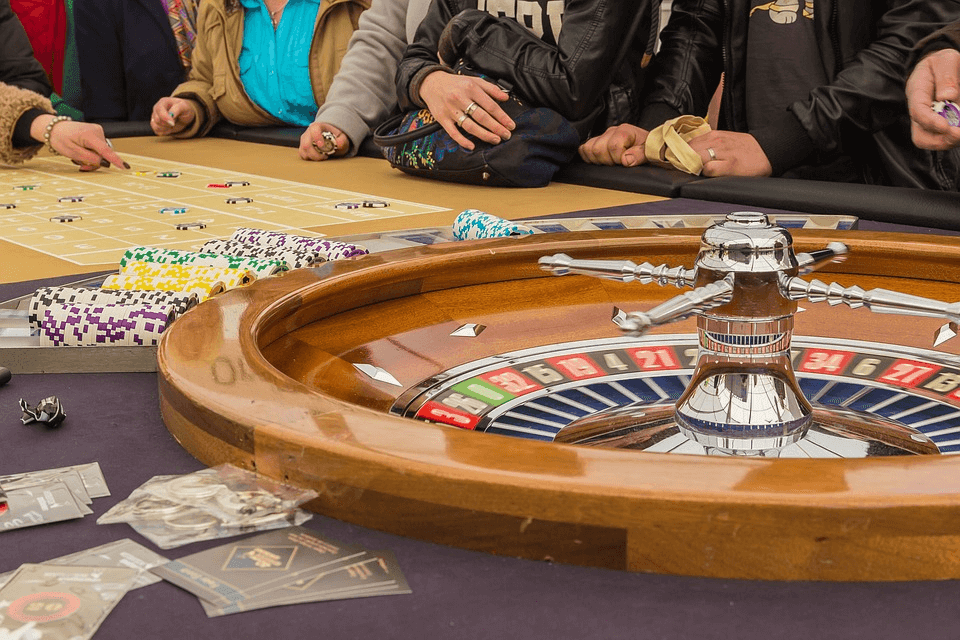 Roulette wheel with chips and players hands visible on the edge of the table