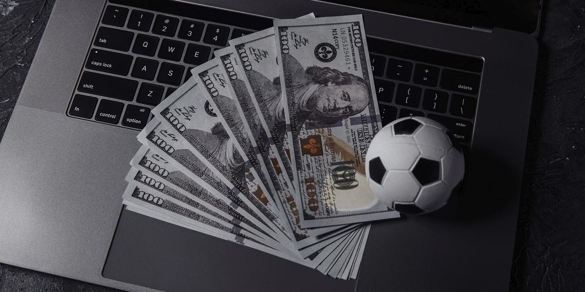 Laptop with money and a small soccer ball on the keyboard