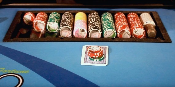 The dealer places the wager on top of their cards. The dealer places the wager on top of their cards.